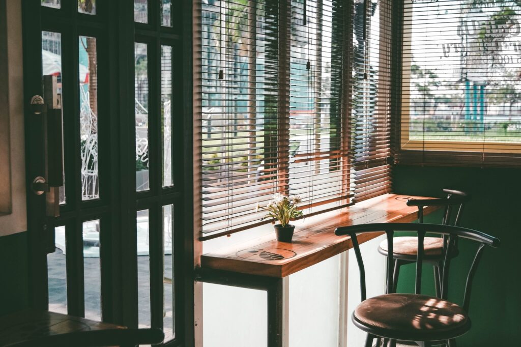 Empty cafe window counter with stools and sunlit blinds