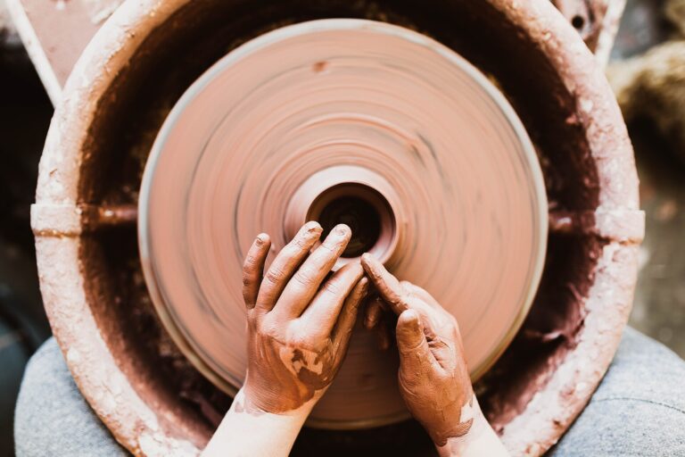 Hands shaping clay on a potter's wheel
